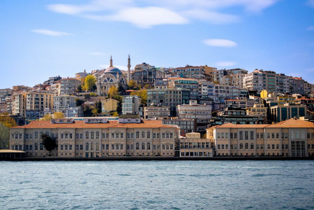 a large body of water with buildings on a hill in the background