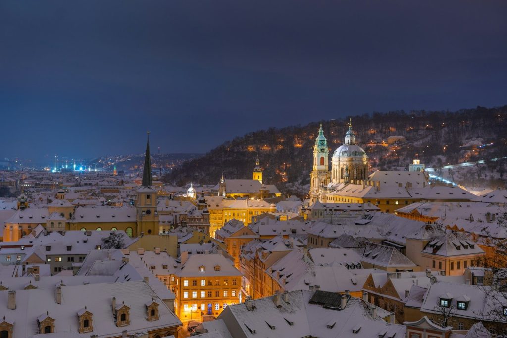 Snow-covered prague cityscape at night with illuminated buildings